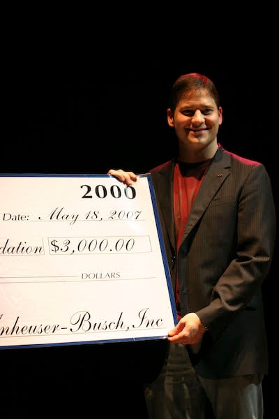 A presenter holding a ceremonial donation check dated May 18, 2007